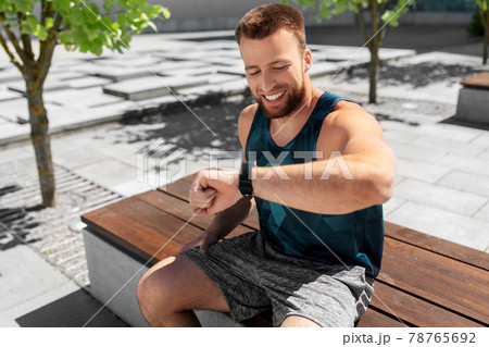 happy man with smart watch sitting on bench 78765692