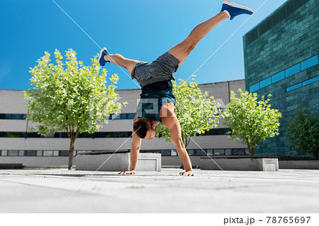 young man exercising and doing handstand outdoors 78765697