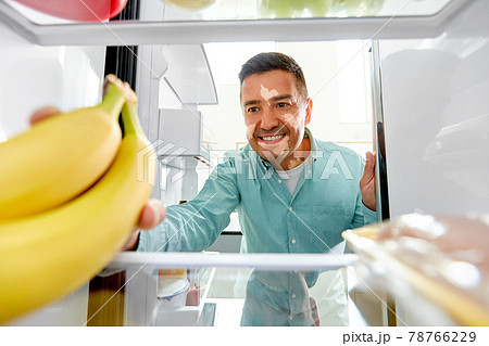 man with vitiligo taking banana from fridge 78766229