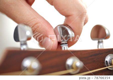 close up of hand tuning guitar strings with pegs close up of hand tuning guitar strings with pegs 78766354