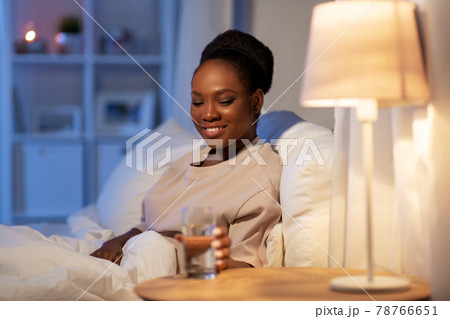 african woman drinking water in bed at night african woman drinking water in bed at night 78766651