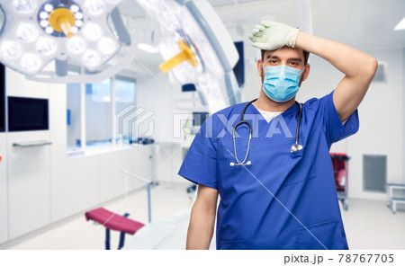 tired male doctor in blue uniform, mask and gloves 78767705