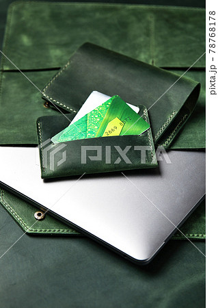 Leather case for a laptop, wallet, business card holder from green leather, handmade products on a wooden table, top view, close-up. 78768178