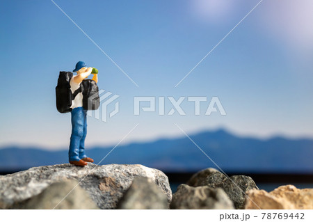 Miniature people : Traveler with backpack walking on the rock Miniature people : Traveler with backpack walking on the rock 78769442