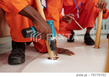 Black man installing screw into table Black man installing screw into table 78770702