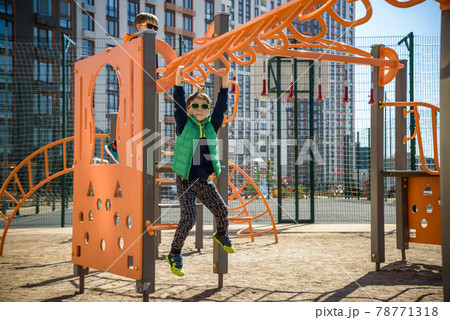 Active little child playing climbing spring metal at school yard playground. Kids play and climb outdoors under sunset, shallow Focus. Active little child playing climbing spring metal at school yard playground. Kids play and climb outdoors under sunset, shallow Focus. 78771318