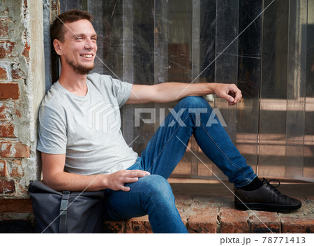Smiling male is sitting on stairs outdoor. Smiling male is sitting on stairs outdoor. 78771413