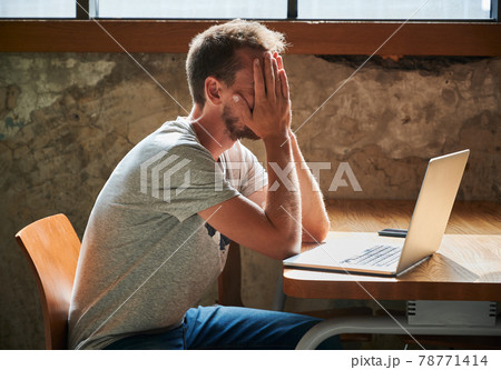Upset man with hands on face tormented by work. Upset man with hands on face tormented by work. 78771414