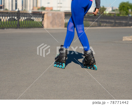 Female legs in roller skates. She rides in the city park and enjoys life. Female legs in roller skates. She rides in the city park and enjoys life. 78771442