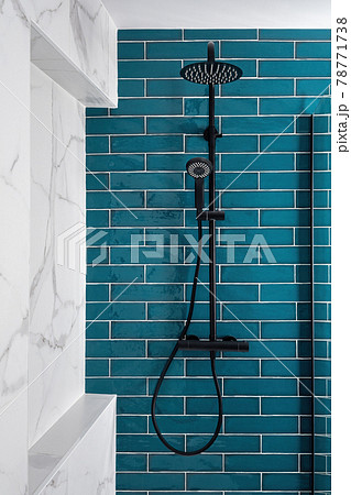 Dark aquamarine and white and color in the bathroom. Modern tiled shower with rain head, hand held shower. Dark aquamarine and white and color in the bathroom. Modern tiled shower with rain head, hand held shower. 78771738