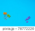 Orange and green metal binder clip or paperclip on blue background with copyspace for text 78772220
