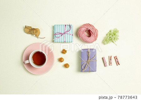 Gift boxes, cup of black tea, pink string, wooden clip, dry flowers on yellow green background. flat lay, top view, copy space Gift boxes, cup of black tea, pink string, wooden clip, dry flowers on yellow green background. flat lay, top view, copy space 78773643