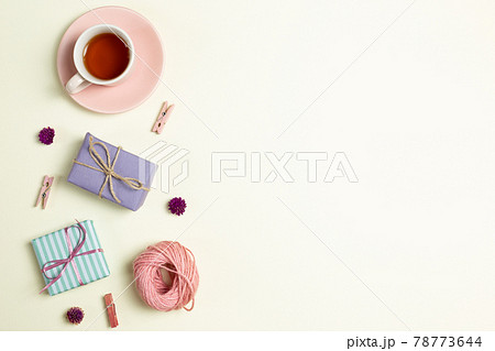 Gift boxes, cup of black tea, pink string, wooden clip, dry flowers on yellow green background. flat lay, top view, copy space 78773644