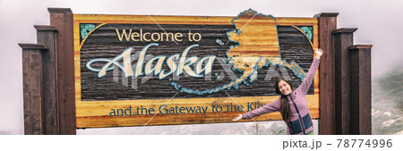 Alaska last frontier border sign tourist chinese woman cruise ship passenger posing at welcome billboard - Happy person traveling in USA panoramic banner. 78774996