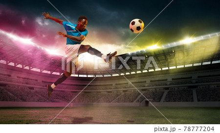 Goal. Male african socce, football player jumping in attack during sport match on cloudt sky background at stadium 78777204