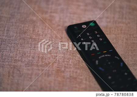 ソファの布地の上に置かれたテレビのリモコン 78780838