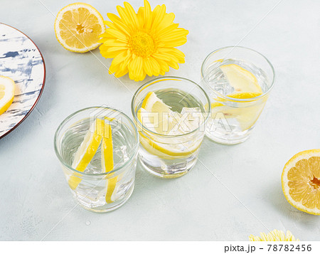 Lemon water drink with ice cubes on stone background with gerbera daisy yellow flowers 78782456