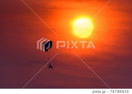 Silhouette of the Paramotor Gliding And Flying In The Air through soft sunlight sunset sky. Silhouette of the Paramotor Gliding And Flying In The Air through soft sunlight sunset sky. 78786910