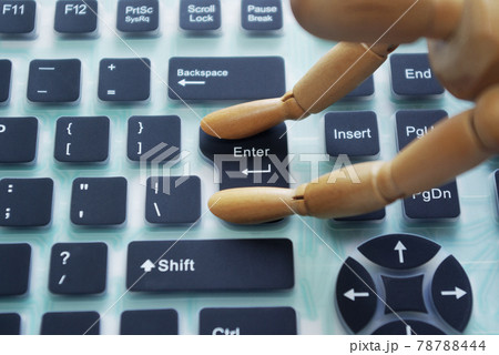 シリコンキーボードのエンターキーを押す木製のモデル人形 78788444