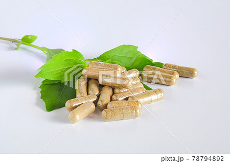 Herbal capsules over green herb leaf on white. Herbal capsules over green herb leaf on white. 78794892