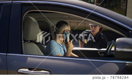 Irritated driver with smartphone speaking with police officer Irritated driver with smartphone speaking with police officer 78798284