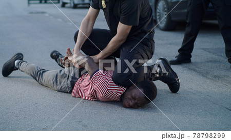 Policeman putting handcuffs on crying black man 78798299