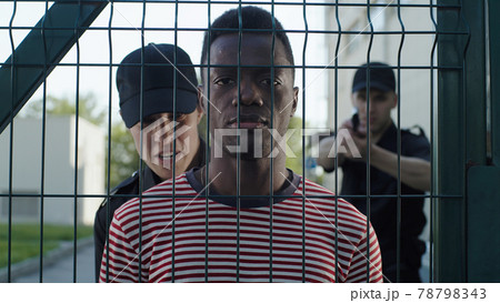 Police office interrogating African American man near grate 78798343