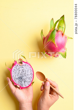 Dragon fruit or pitaya holding by woman hand with spoon on yellow background 78800044