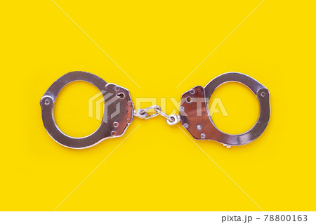 Metal handcuffs on yellow background Metal handcuffs on yellow background 78800163