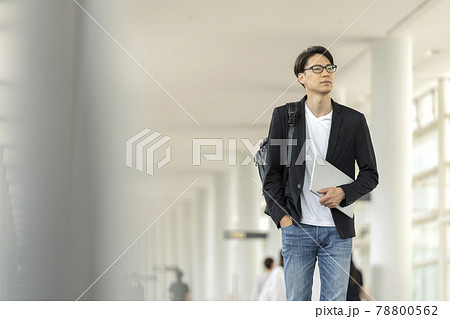 ノートパソコンとバックパックを持って歩く30代の男性 78800562