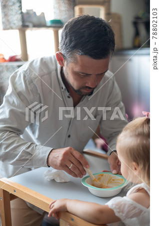 The Caucasian man lies on his back and holds his daughter above him in the children's room 78802103