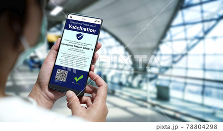 Traveler holds vaccine passport certificate to show COVID 19 vaccination status 78804298
