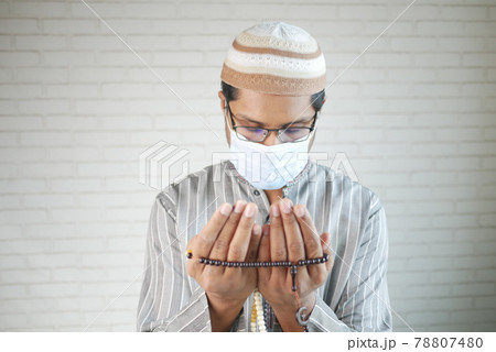 muslim man with face mask keep hand in praying gestures during ramadan, 78807480