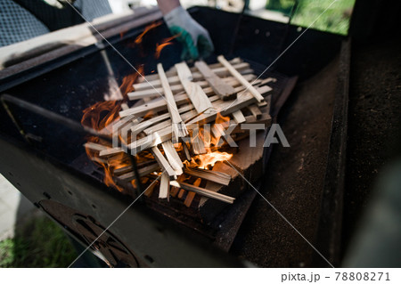 A man in gloves kindles fire from stacked wood. Preparation for a barbecue. A man in gloves kindles fire from stacked wood. Preparation for a barbecue. 78808271