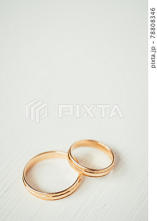 Intersecting wedding gold rings at the bottom of the white wooden background. Vertical. 78808346