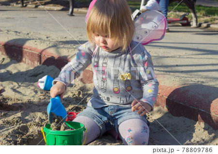 Beautiful little girl with fairy wings playing the sand Beautiful little girl with fairy wings playing the sand 78809786