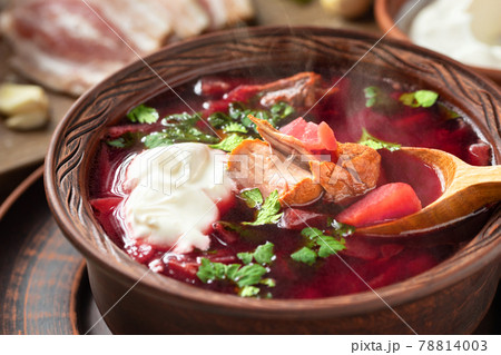 Freshly cooked borscht - traditional dish of Russian and Ukrainian cuisine in earthenware dishes with bacon, bread, sour cream and garlic, close up 78814003