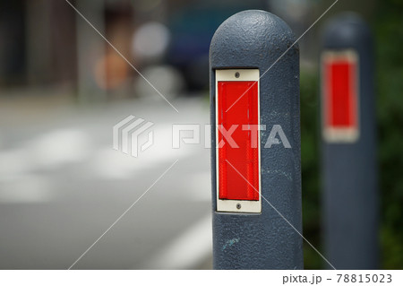 赤い反射板のある歩道沿いの安全ポールの写真素材