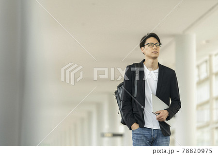 ノートパソコンとバックパックを持って歩く30代の男性　カジュアルビジネス　イメージ 78820975