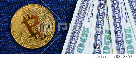 Golden Bitcoin and dollar bills lies on a blue jeans fabric. New virtual money. New crypto currency in the form of the coins Golden Bitcoin and dollar bills lies on a blue jeans fabric. New virtual money. New crypto currency in the form of the coins 78828352