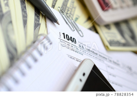 The pen, notebook, calculator, smartphone and dollar bills is lies on the tax form 1040 U.S. Individual Income Tax Return. The time to pay taxes 78828354