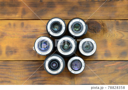 Several photographic lenses lie on a brown wooden background. Space for text Several photographic lenses lie on a brown wooden background. Space for text 78828358