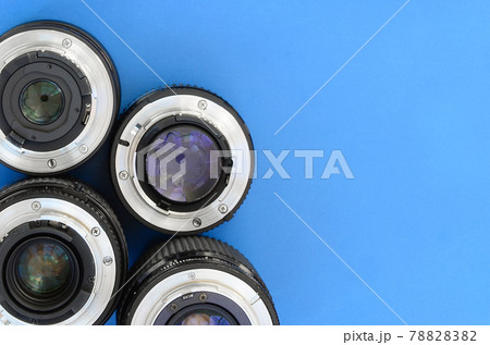 Several photographic lenses lie on a bright blue background. Space for text 78828382