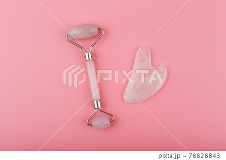 Top view of jade roller and heart shaped massager made of pink quartz on pink background. Guasha massage concept Top view of jade roller and heart shaped massager made of pink quartz on pink background. Guasha massage concept 78828843
