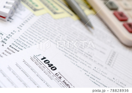 The pen, notebook, calculator, and dollar bills is lies on the tax form 1040 U.S. Individual Income Tax Return. The time to pay taxes 78828936