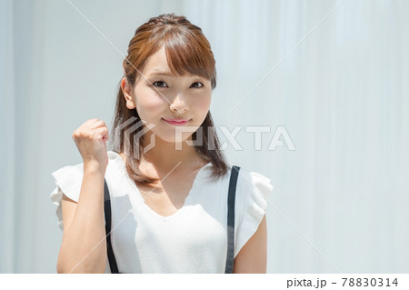 白壁の前で日差しを受ける夏服の若い女性 78830314