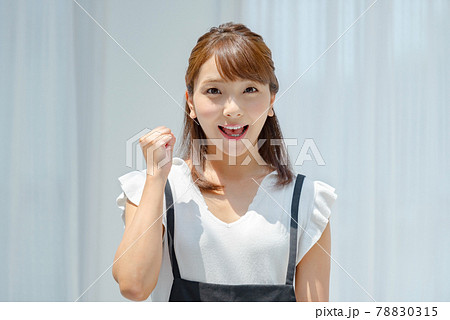 白壁の前で日差しを受ける夏服の若い女性 78830315