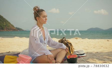 The cheerful woman in holding and eating slices of watermelon on tropical sand beach sea. Portrait attractive girl spend summer weekend. The cheerful woman in holding and eating slices of watermelon on tropical sand beach sea. Portrait attractive girl spend summer weekend. 78830632