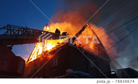 The roof of the house is on fire. The residential building burn, village. Firefighters put out a fire from the crane from above. Smoke and sparks. The roof of the house is on fire. The residential building burn, village. Firefighters put out a fire from the crane from above. Smoke and sparks. 78830674