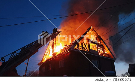 The roof of the house is on fire. The residential building burn, village. Firefighters put out a fire from the crane from above. Smoke and sparks. The roof of the house is on fire. The residential building burn, village. Firefighters put out a fire from the crane from above. Smoke and sparks. 78830675